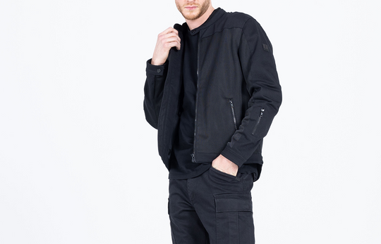 Model wearing the John Doe Aero Mesh Jacket in black – front angle, hands in pockets, white background