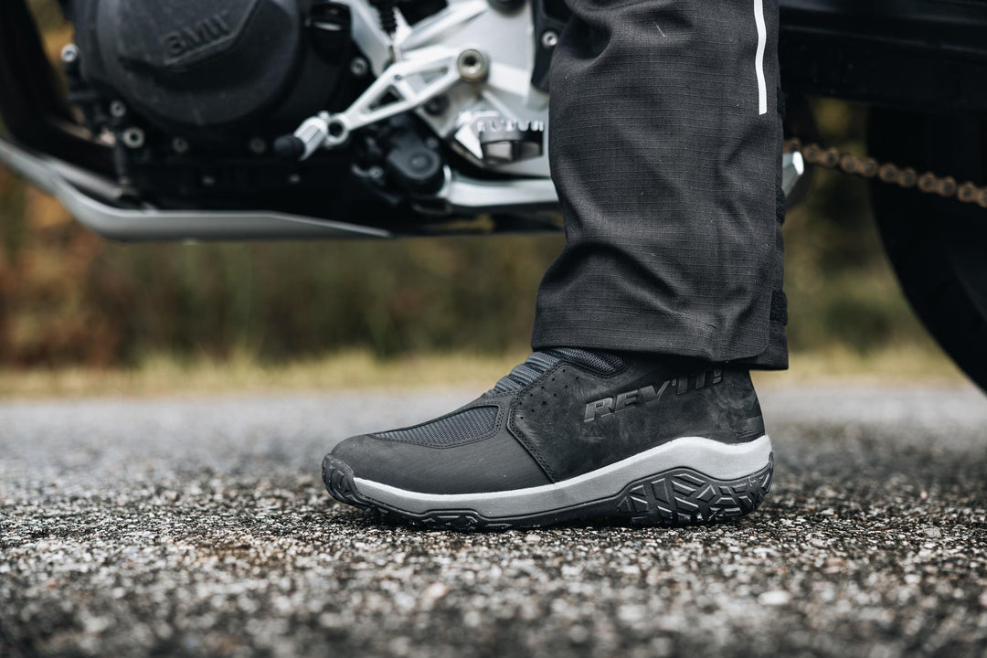 Boundless H2O ADV Footwear close-up worn beside an adventure motorcycle.