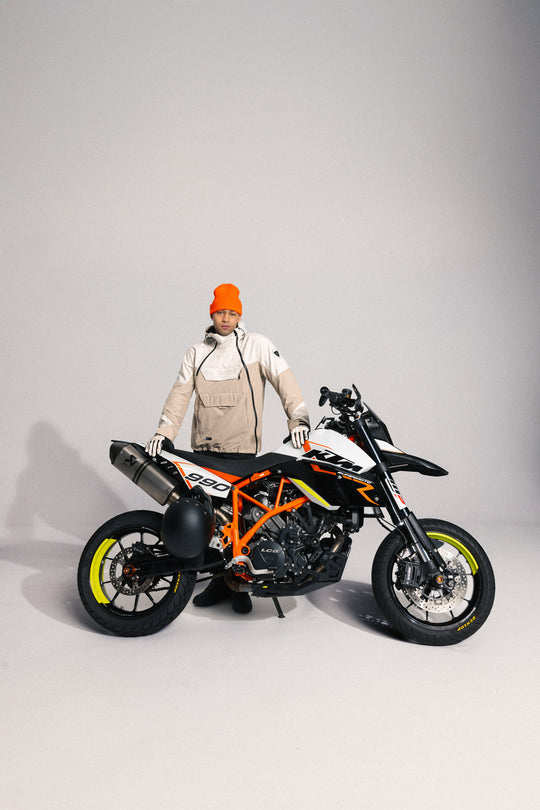 Model wearing REV’IT! Altair H2O Smock, Sand, front view behind motorbike