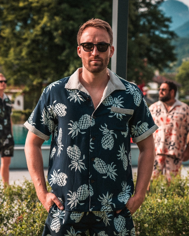 Man wearing Pike Brothers 1961 Cabana Shirt in Entrega Blue with matching shorts, standing outdoors in summer light
