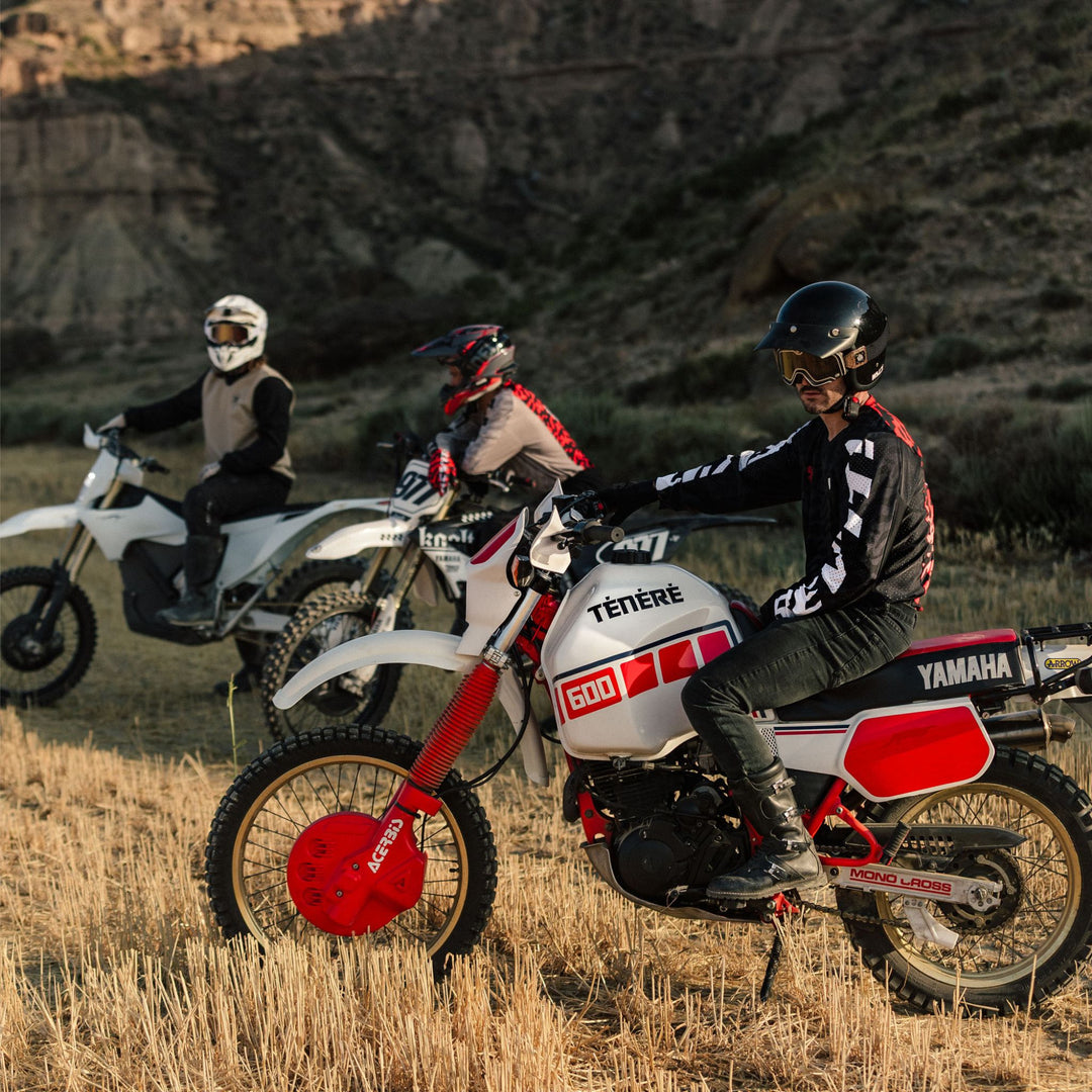 Rider wearing REV’IT! Thirteen Jersey in Black/Sand colourway on a Yamaha Ténéré, off-road with other motorcyclists in the background.