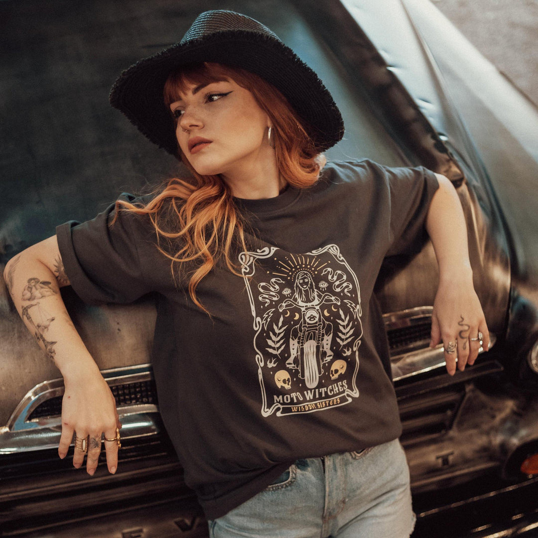Wildust Sisters Moto Witches T-Shirt styled with denim shorts and black hat in front of classic car
