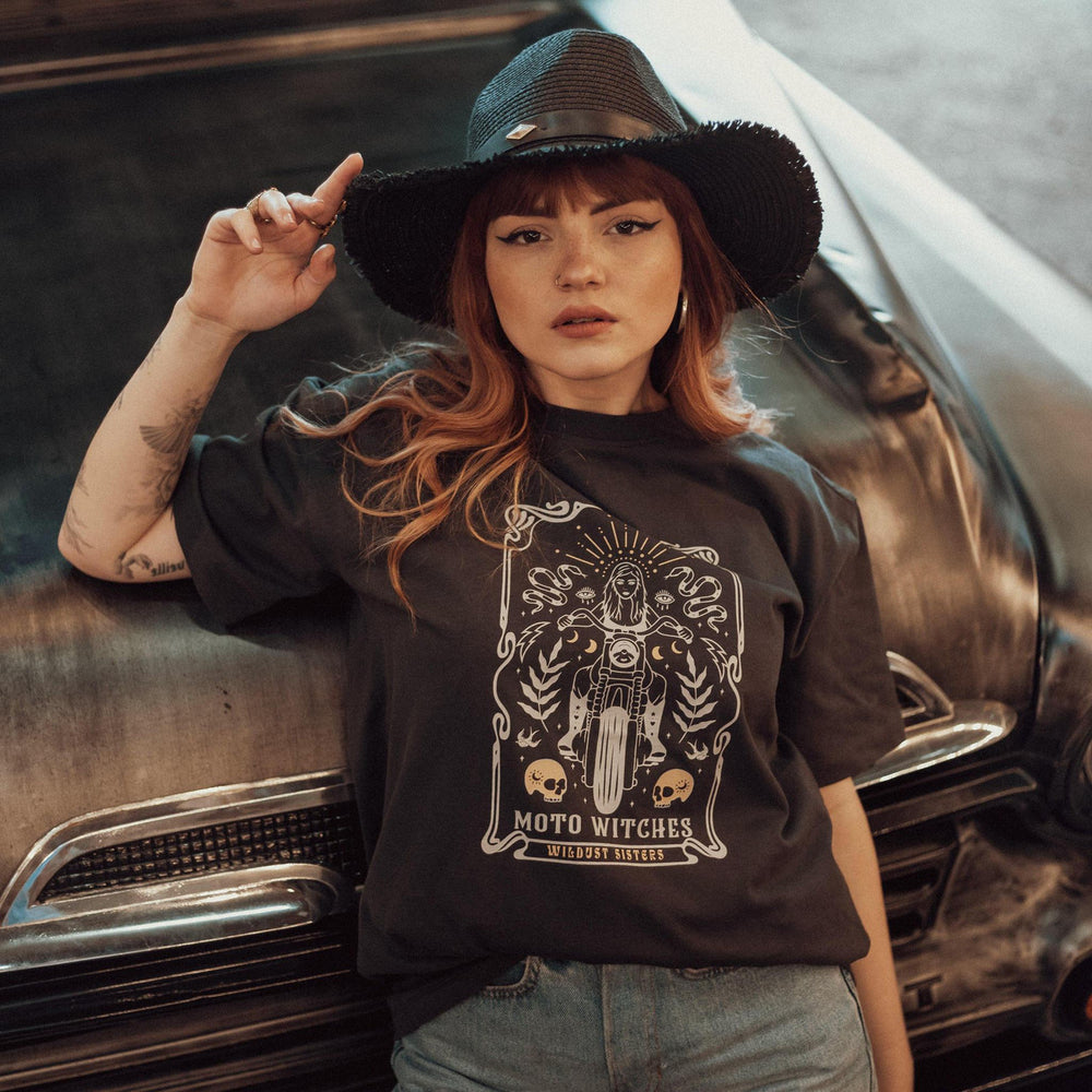 Woman wearing Wildust Sisters Moto Witches T-Shirt standing in front of a vintage car