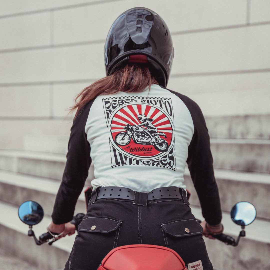 Rider on a red motorcycle wearing the Wildust Sisters Rebel Long Sleeve Tee with black sleeves and race-inspired back print, paired with black Wildust Overland trousers.