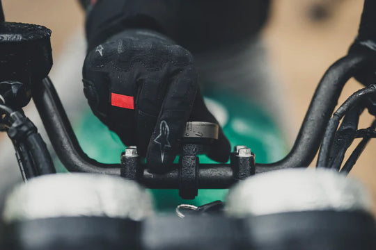Gloved rider pressing Beeline Moto II device onto Bar Clamp Mount in use