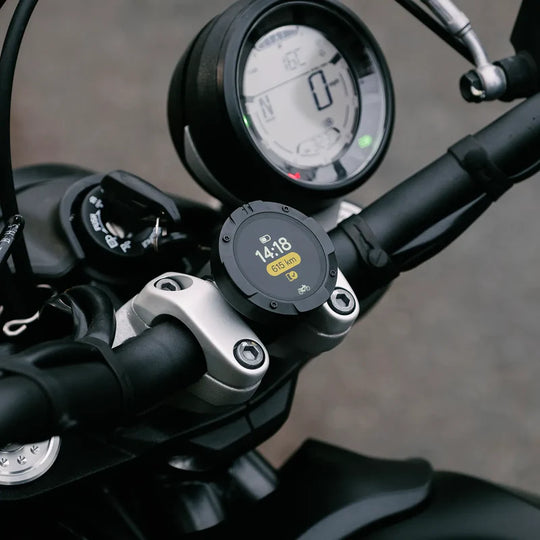 Beeline Moto II mounted on motorcycle handlebars showing ride data screen with time and distance