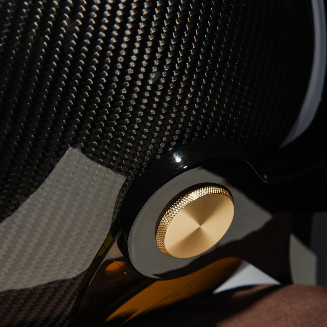 Close-up of the Hedon Psilo Explorer Helmet – Commander highlighting the gold visor pivot hardware and exposed carbon fibre shell with the tinted visor visible underneath.