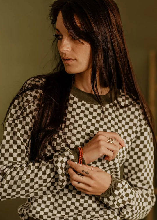 Model wearing the Wildust Sisters Vintage Racing Jumper in Khaki showcasing the slim fit and classic chequered knit