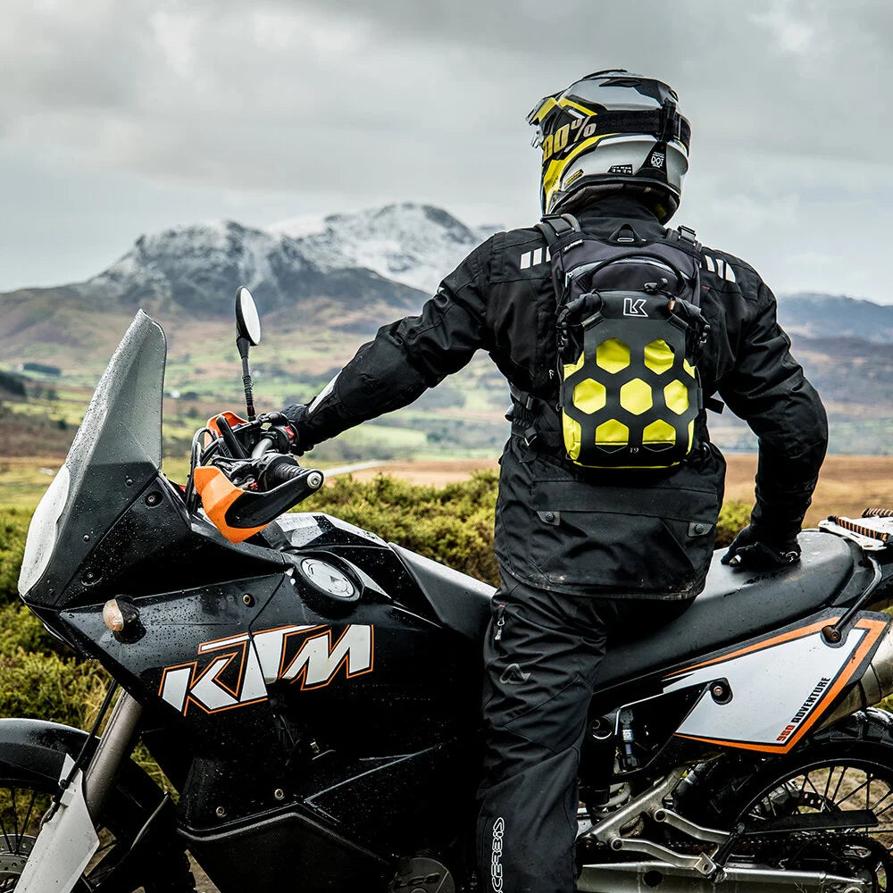 Rider wearing Kriega Trail 9 lime motorcycle backpack on KTM adventure bike