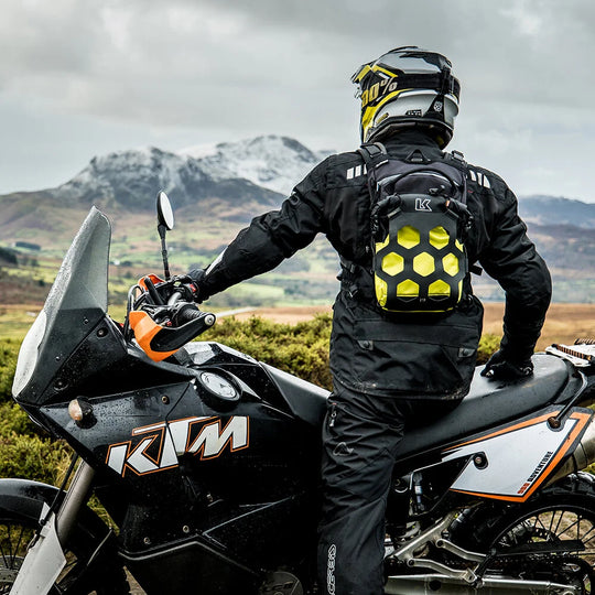 Rider wearing Kriega Trail 9 lime motorcycle backpack on KTM adventure bike