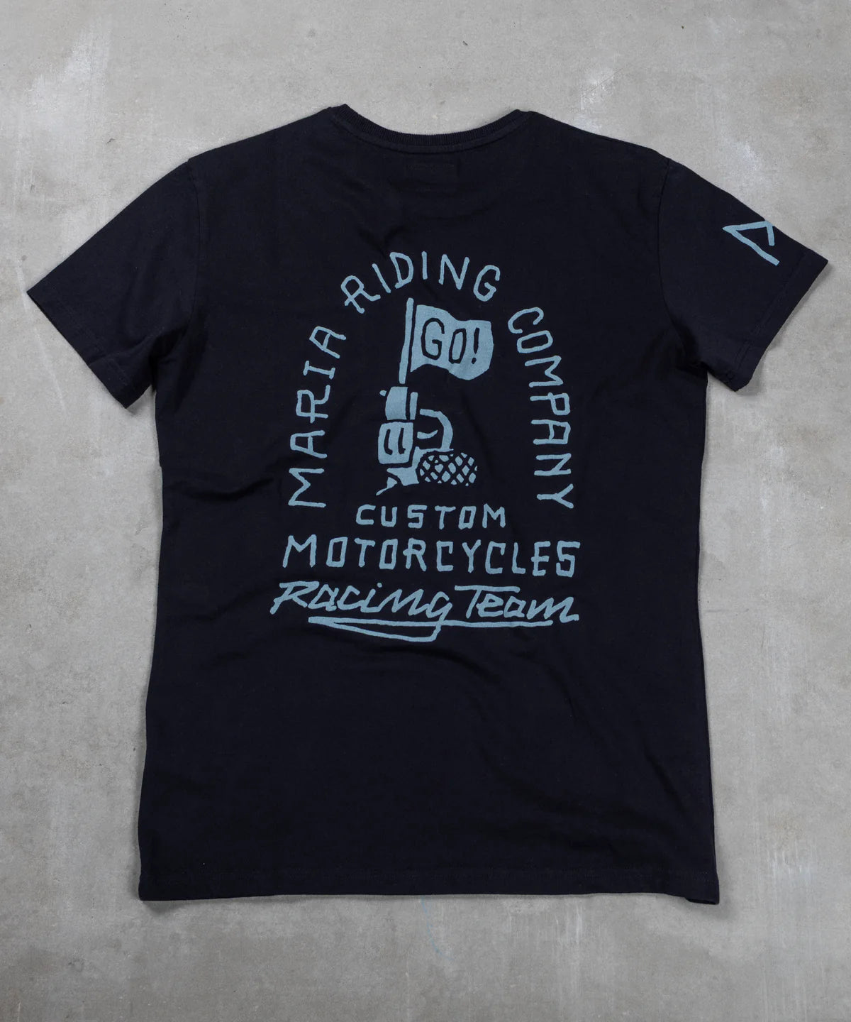 Black t-shirt with white graphic design on a gray concrete surface