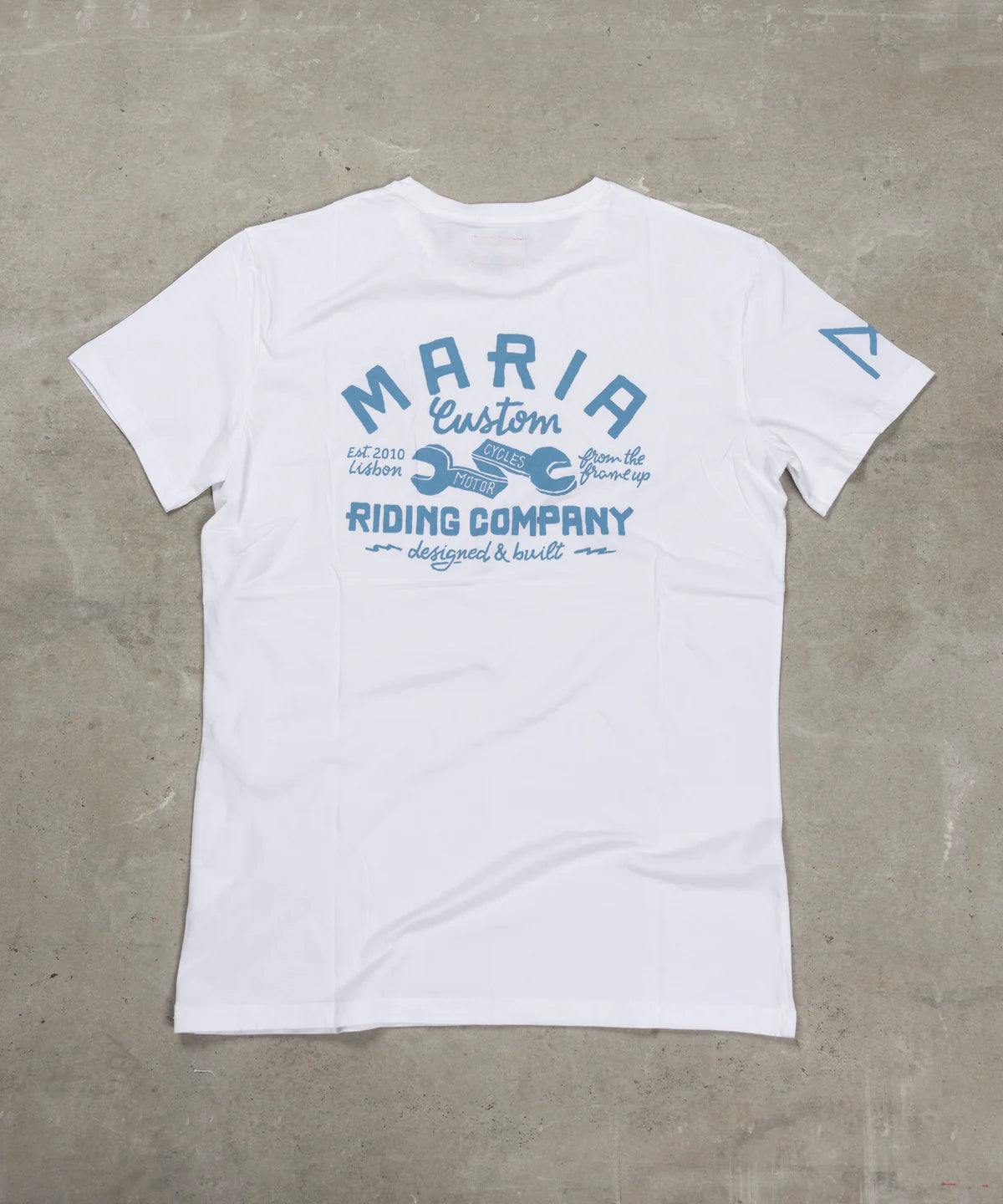 White t-shirt with blue graphic design on a gray surface