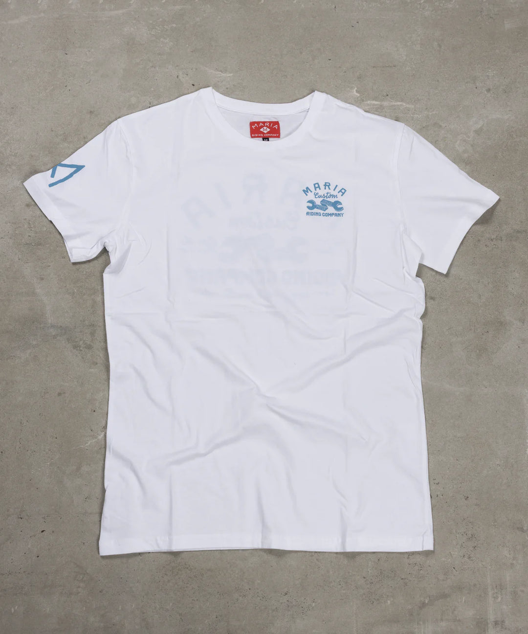 White t-shirt with blue graphics and text on a gray surface
