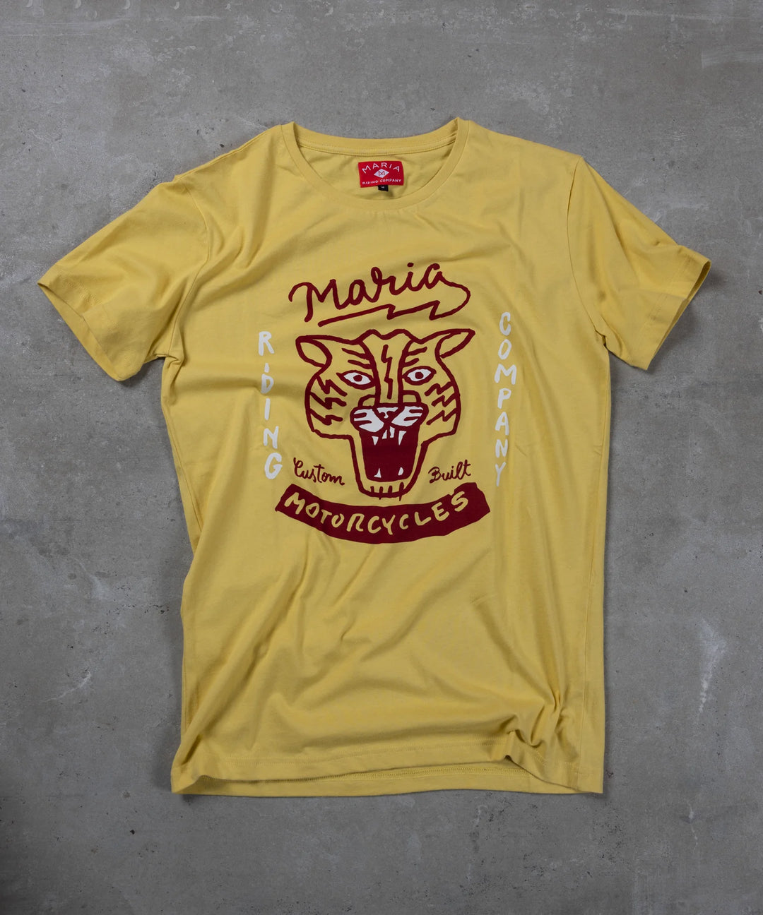 Yellow t-shirt with red graphic design on a gray surface