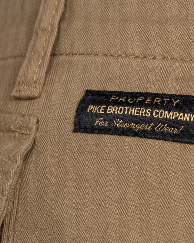 Close-up of Pike Brothers badge and olive herringbone fabric on 1944 Monkey Pant