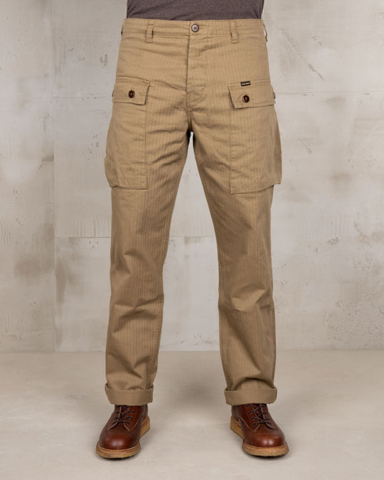 Close-up front view of Pike Brothers 1944 Monkey Pant in Olive showing waist and hips – model wearing brown boots