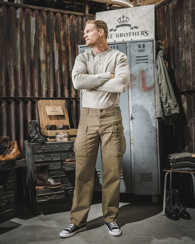 Front view of male model wearing Pike Brothers 1944 Monkey Pant in Olive – shop setting