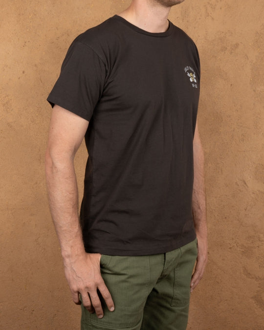 Model wearing Pike Brothers 1969 Jolly Roger Tee in Black with olive cargo pants – side view