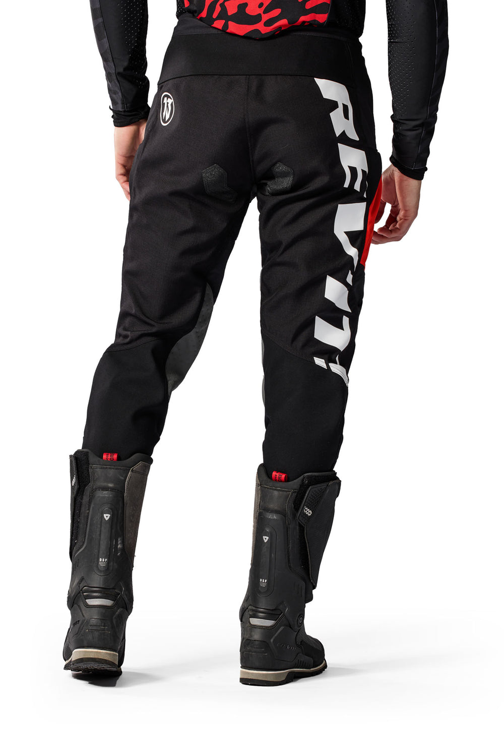 Model wearing REV’IT! Lejano Motorcycle Trousers in black and red, rear view.
