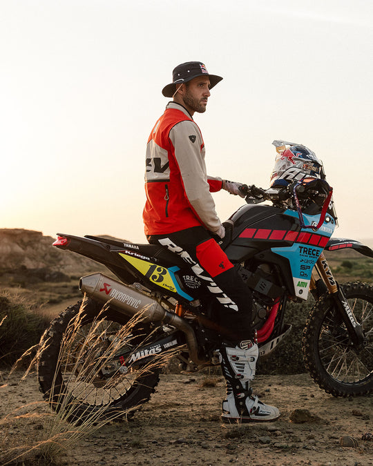 Model wearing REV’IT! Lejano Motorcycle Trousers standing beside an off-road motorcycle.
