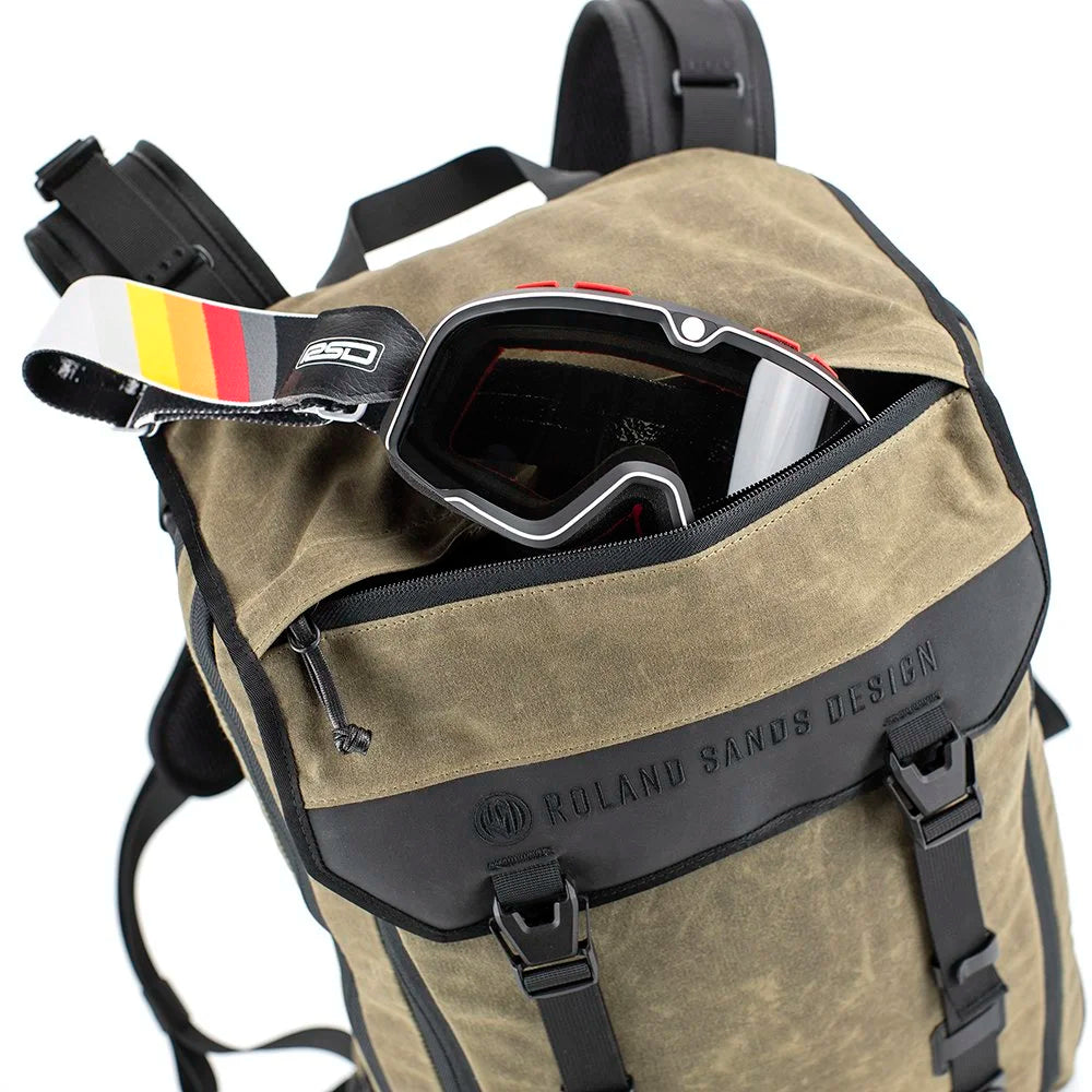 Roland Sands Design x Kriega Roam 34 Backpack in brown with motocross goggles stored in front pocket on white background