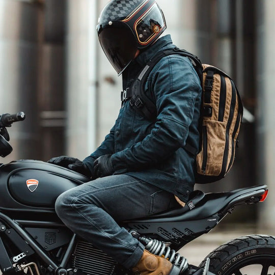 Rider with Roland Sands Design x Kriega Roam 34 Backpack in brown sitting on motorcycle in urban setting