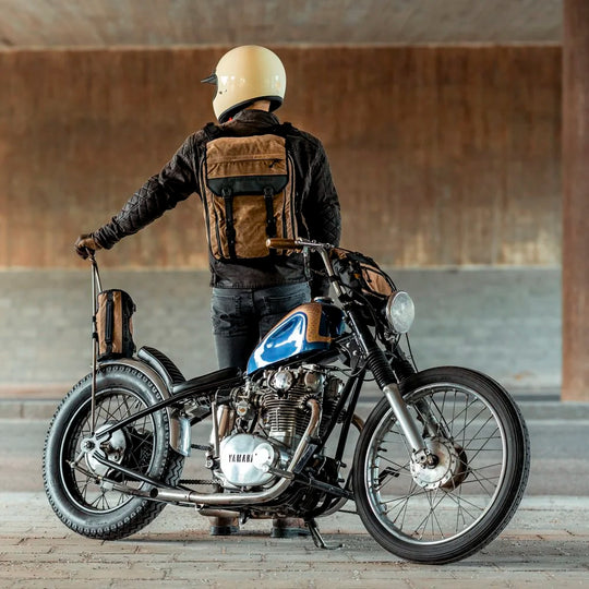 Rider wearing Roland Sands Design x Kriega Roam 34 Backpack in brown, standing by motorcycle