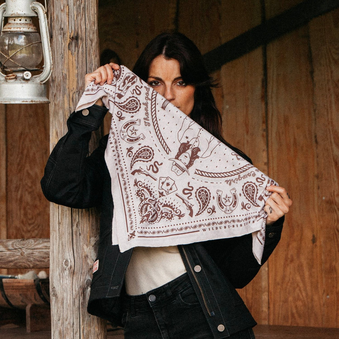 Rider holding Wildust Sisters Best in the West Scarf showing western artwork in ecru and brown