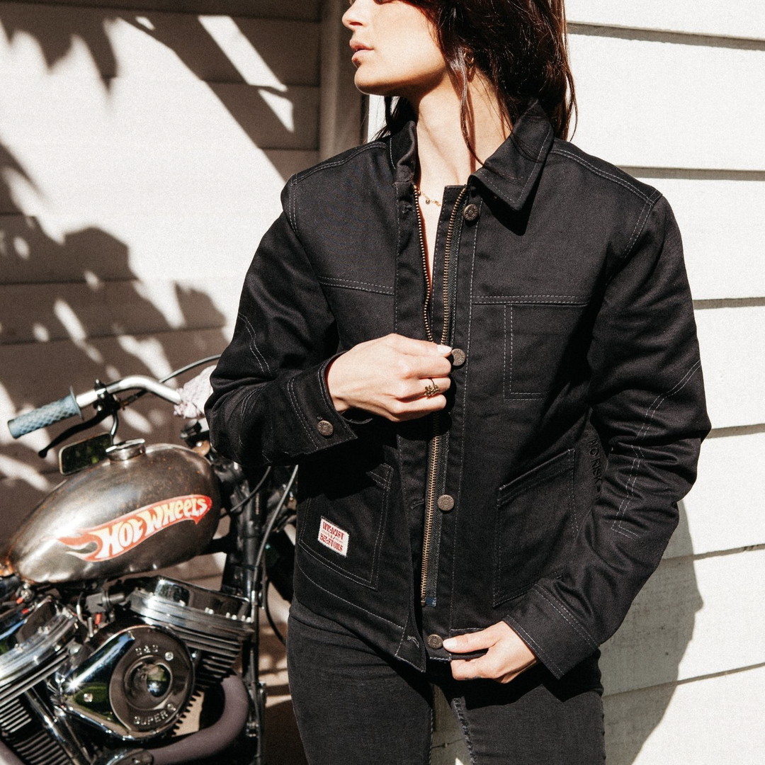 Front view of female rider zipping up Wildust Sisters Pioneer Jacket in Black, wearing a gold ring