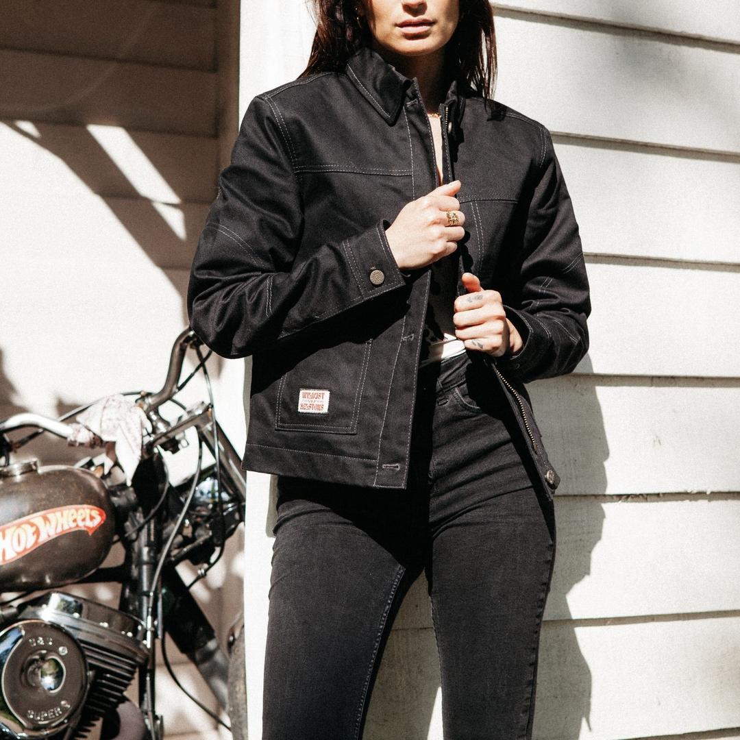 Female rider wearing Wildust Sisters Pioneer Jacket in Black, holding jacket closed