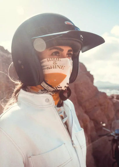 Rider wearing Wildust Sisters Ride & Shine Scarf under helmet – khaki, ecru and orange Lycra motorcycle bandana